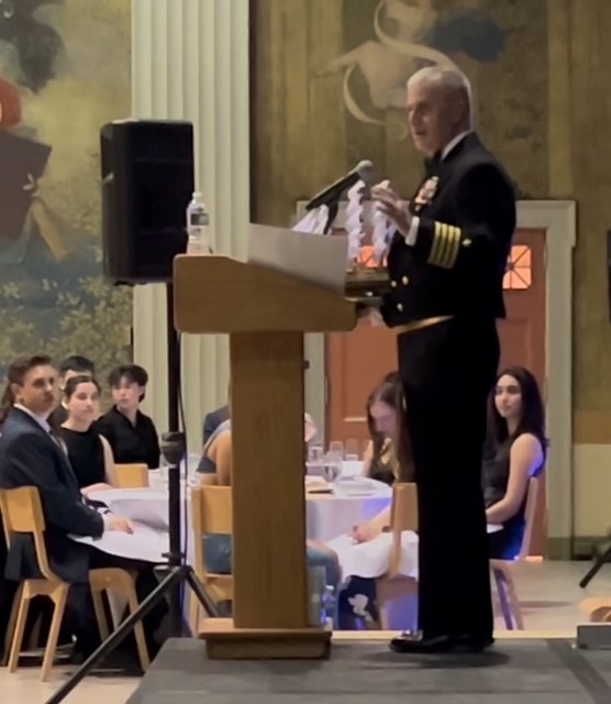Captain Jack Houdeshell speaks at a podium at the MIT Joint Services Military Ball.