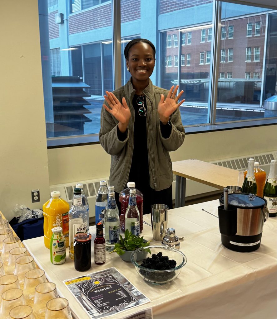 A student server stands with the ingredients for making mocktails.